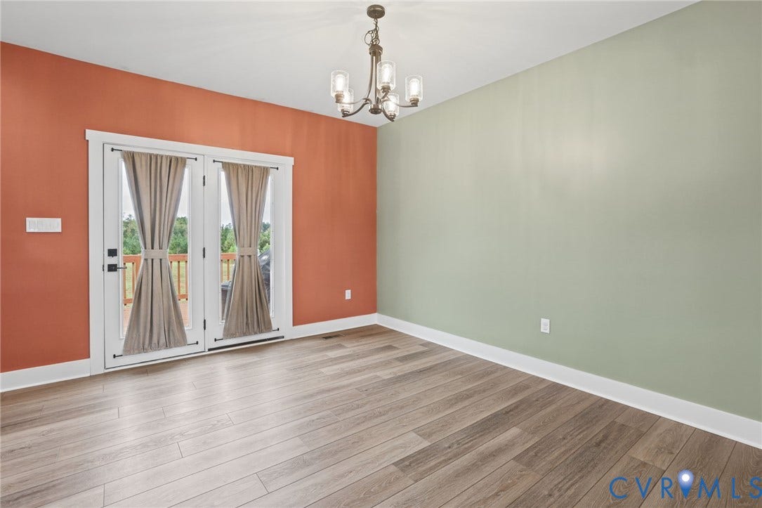 Wood-finish flooring, white trim, and a multi-light chandelier