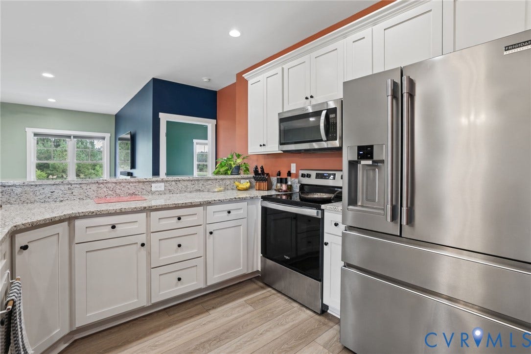 White cabinetry, stainless steel appliances, light-toned wood-finish flooring, and a stone-finish countertop