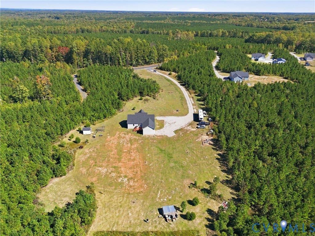 Expansive lot featuring a single-story residence, gravel driveway, and surrounding mature trees
