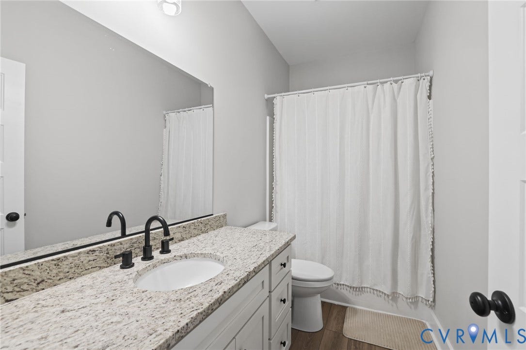 White vanity with a light granite countertop, undermount sink, and matte black fixtures