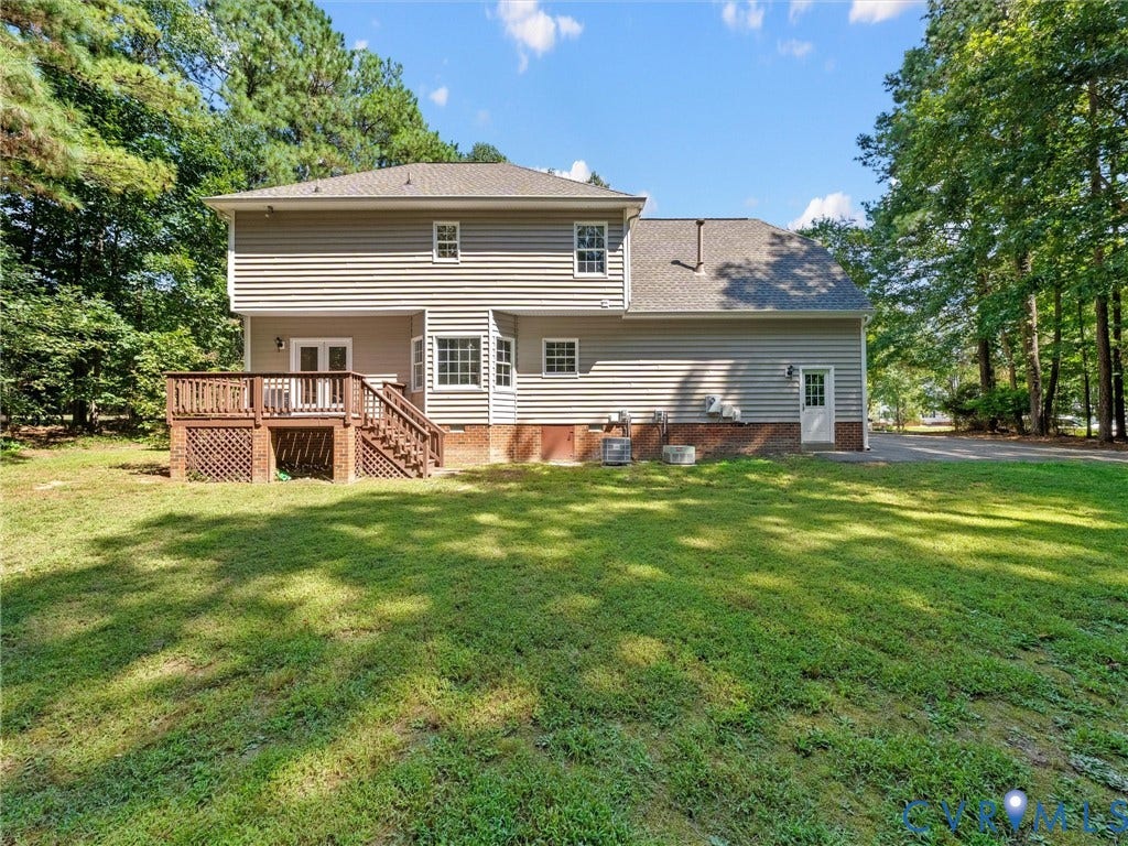 12000 Glen Kilchurn Drive, Chesterfield, VA 23838 Expansive backyard featuring a wood deck with lattice skirting, double doors, multiple windows, and a paved driveway