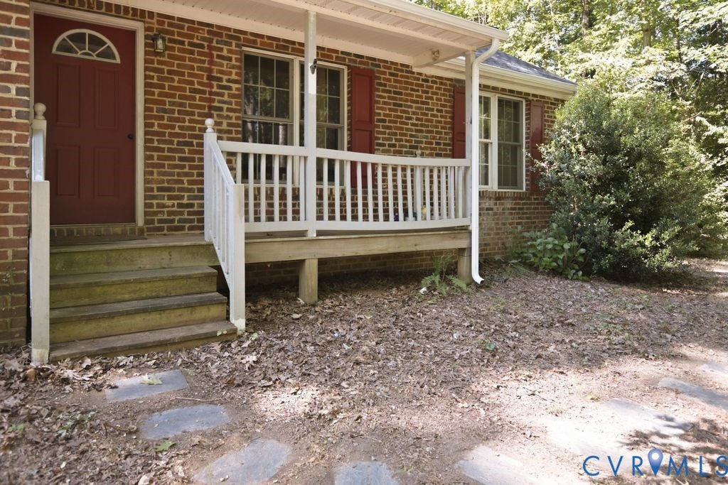 Brick exterior with red shutters and a covered porch