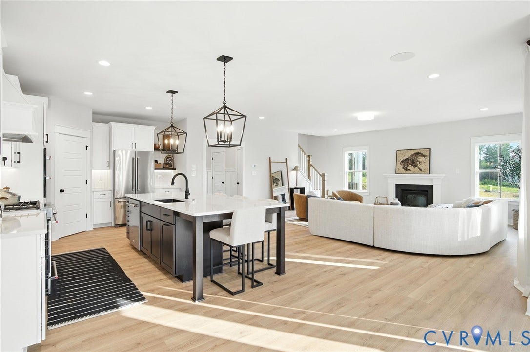 Lot 1 Needlewood Court, Olivet Church Estates, New Kent, VA 23124 Open-concept living area with wood-finish flooring, a kitchen island, and a fireplace with a white mantel