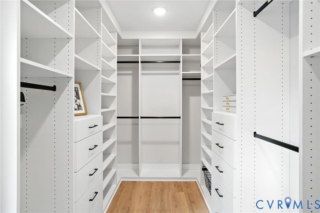 Lot 1 Needlewood Court, Olivet Church Estates, New Kent, VA 23124 Custom closet system featuring extensive shelving, built-in drawers with black hardware, garment rods, and wood-finish flooring