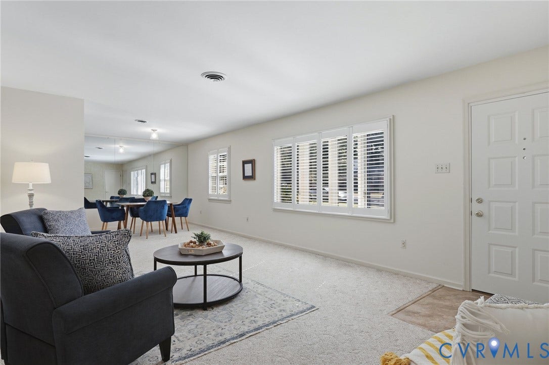 4810 Conduit Road, Colonial Heights, VA 23834 Open-concept living area with carpet flooring, white paneled entry door, and multiple windows with white plantation shutters