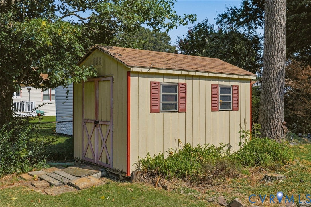 4810 Conduit Road, Colonial Heights, VA 23834 Detached storage shed with two windows, red decorative shutters, and a wood-panel exterior