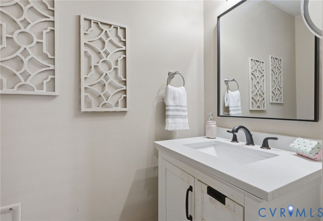 4810 Conduit Road, Colonial Heights, VA 23834 White vanity with black hardware, integrated sink, dark bronze-finish faucet, and framed mirror