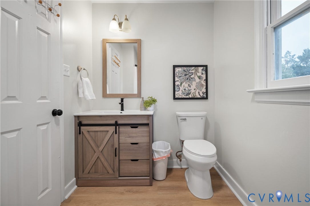 4525 Old Mesa Drive, North Chesterfield, VA 23237 Modern bathroom featuring a wood-finish vanity with barn door style cabinet and drawer storage, a rectangular sink, matte black faucet, and wood-finish flooring