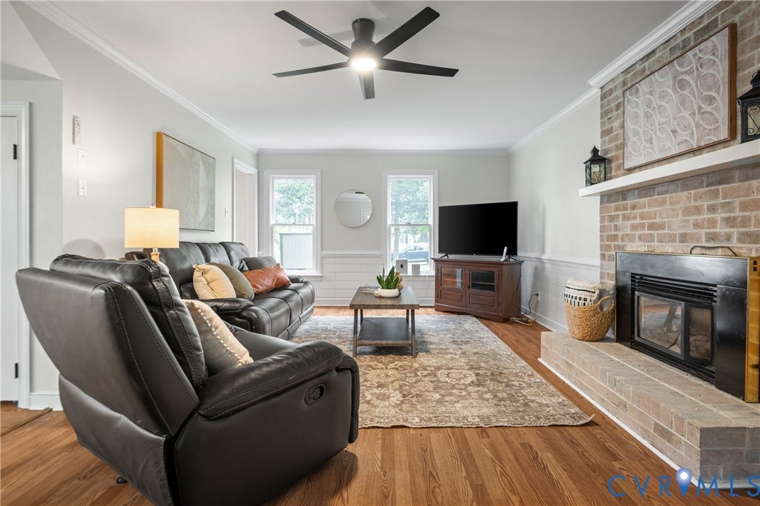 4525 Old Mesa Drive, North Chesterfield, VA 23237 Living area featuring wood-finish flooring, a brick fireplace with a hearth, crown molding, and a ceiling fan with integrated lighting