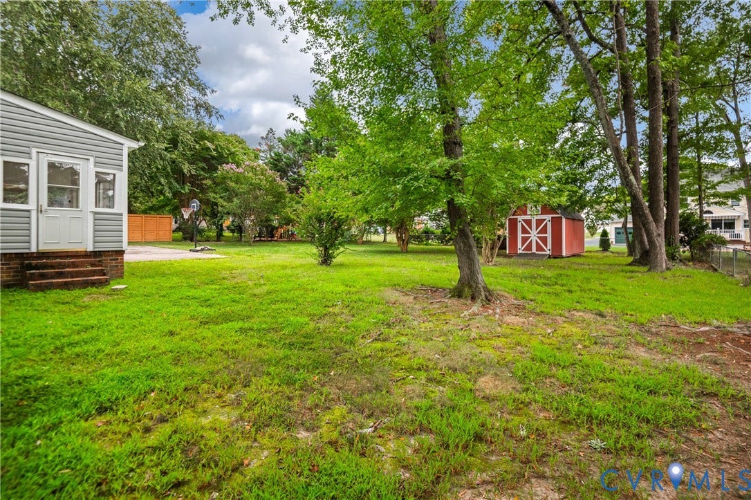 4525 Old Mesa Drive, North Chesterfield, VA 23237 Expansive green lawn with mature trees and a red storage shed