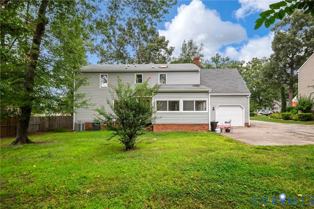 4525 Old Mesa Drive, North Chesterfield, VA 23237 Rear elevation featuring light gray siding, a brick foundation, a single-car garage, and a fenced yard