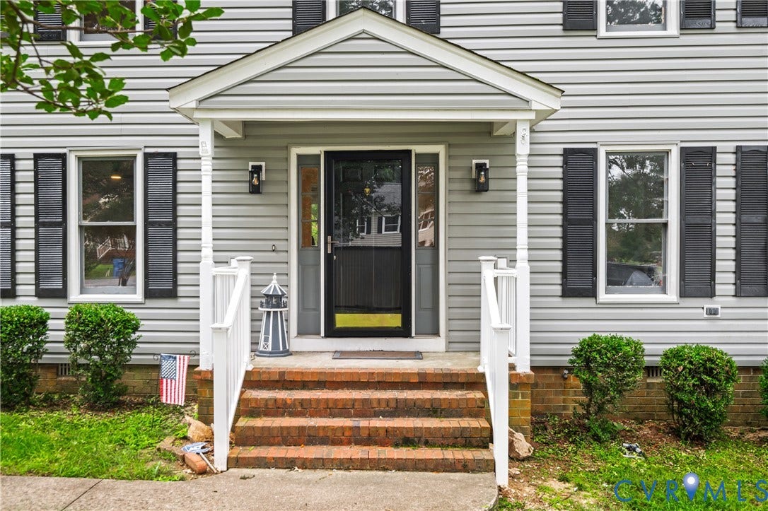 4525 Old Mesa Drive, North Chesterfield, VA 23237 Covered entryway with brick steps, white railing, and dual exterior wall sconces