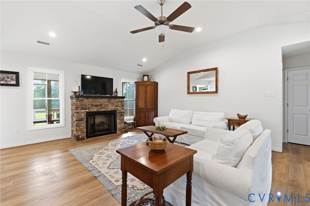 2927 Poorhouse Road, 522 Corridor, Goochland, VA 23063 Living area featuring LVP flooring, a stone-front fireplace with a mantel, white walls, and a vaulted ceiling with a ceiling fan