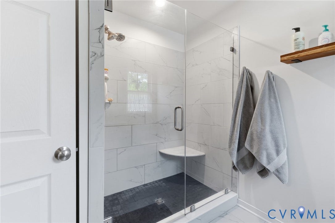2927 Poorhouse Road, 522 Corridor, Goochland, VA 23063 Glass-enclosed shower with white marble-look tile walls, a built-in corner bench, and dark-toned shower floor tile