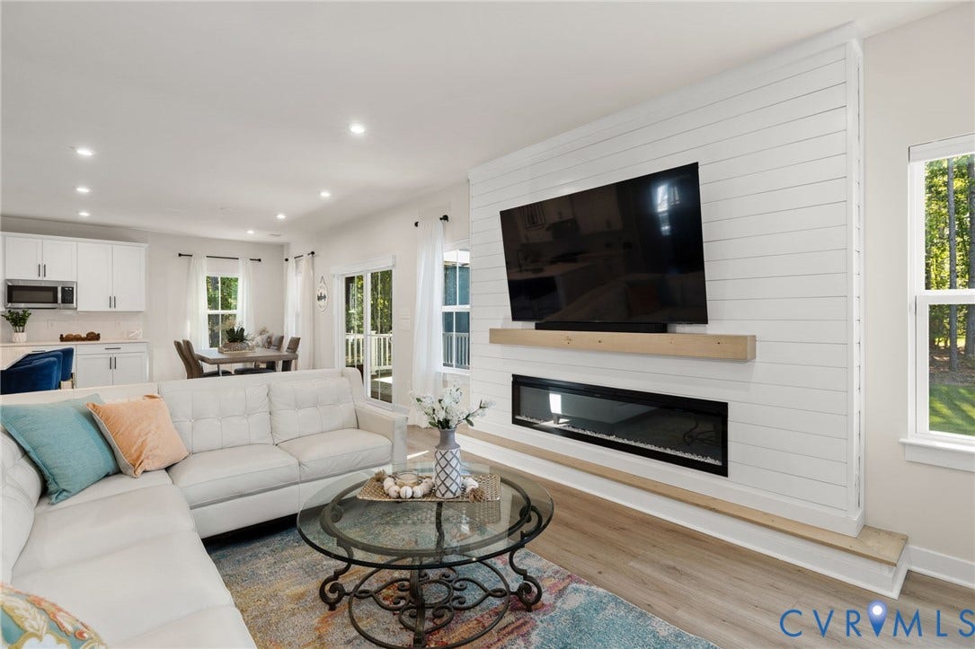8618 McKibben Drive, The Highlands, Chesterfield, VA 23838 Open-concept living space featuring a linear electric fireplace with a wood mantel, white shiplap accent wall, recessed lighting, and wood-finish flooring