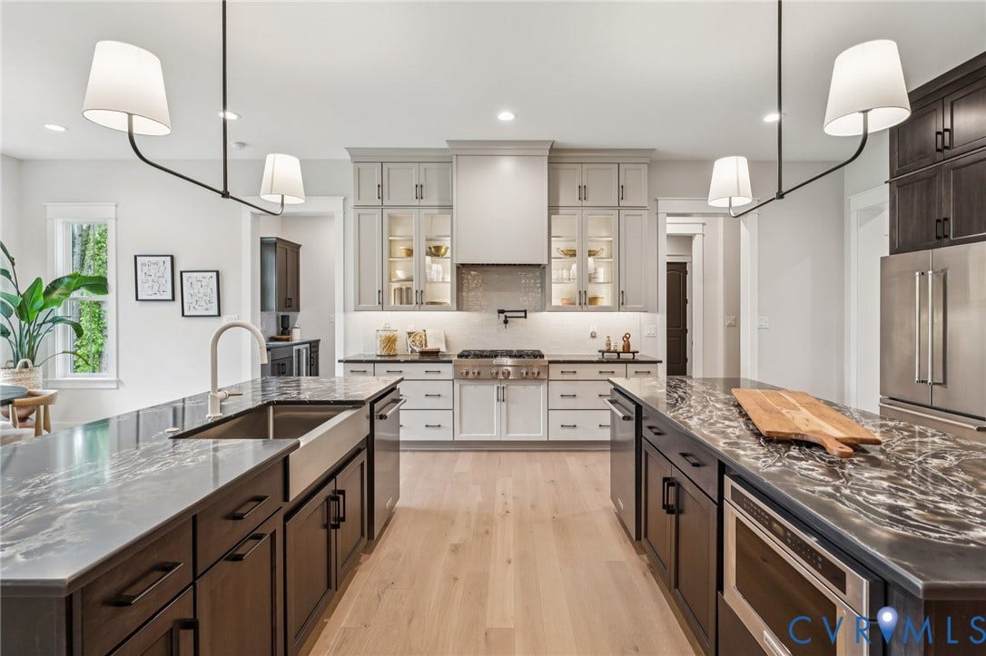 Lot 2 Needlewood Court, Olivet Church Estates, New Kent, VA 23124 Gourmet kitchen featuring two islands with stone countertops, a farmhouse sink, stainless steel appliances, and custom cabinetry with illuminated glass-front uppers