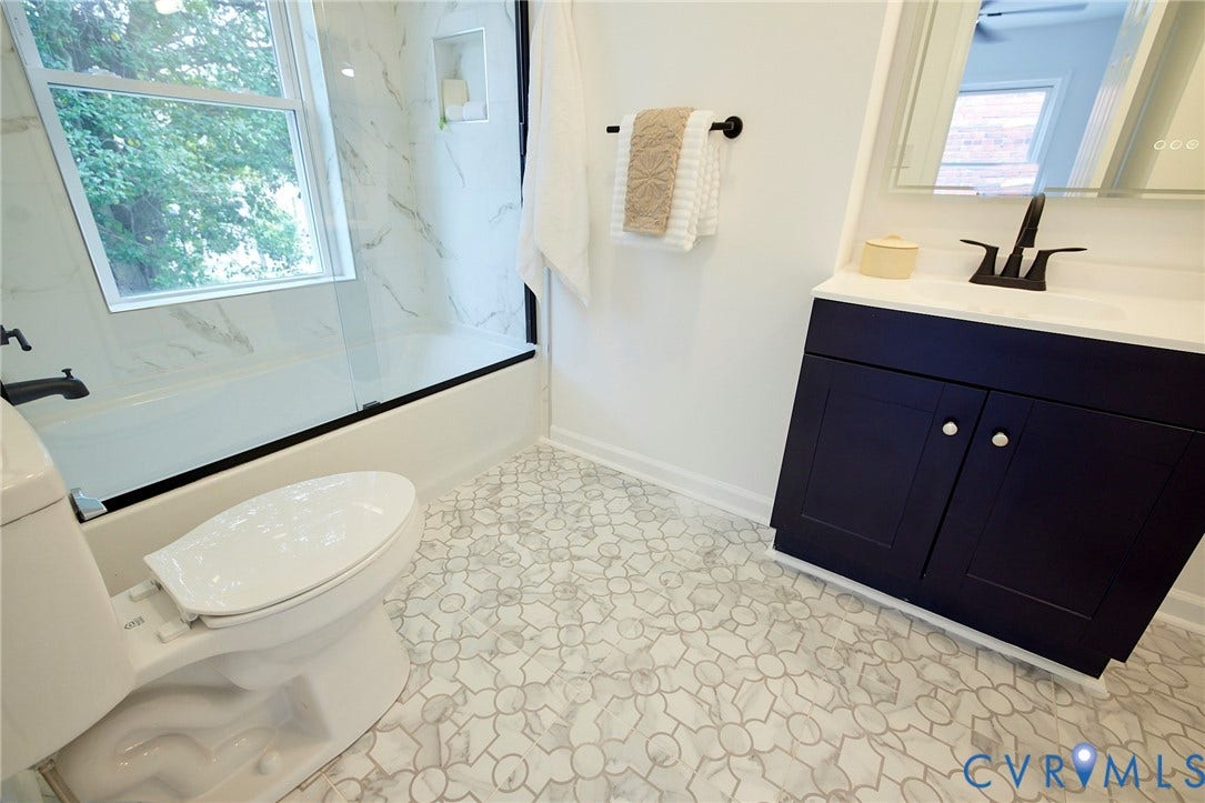 3103 Q St, Church Hill, Richmond, VA 23223 Patterned mosaic tile flooring, contemporary vanity with an integrated sink, black-finish faucet, and a shower/tub combination with a glass enclosure
