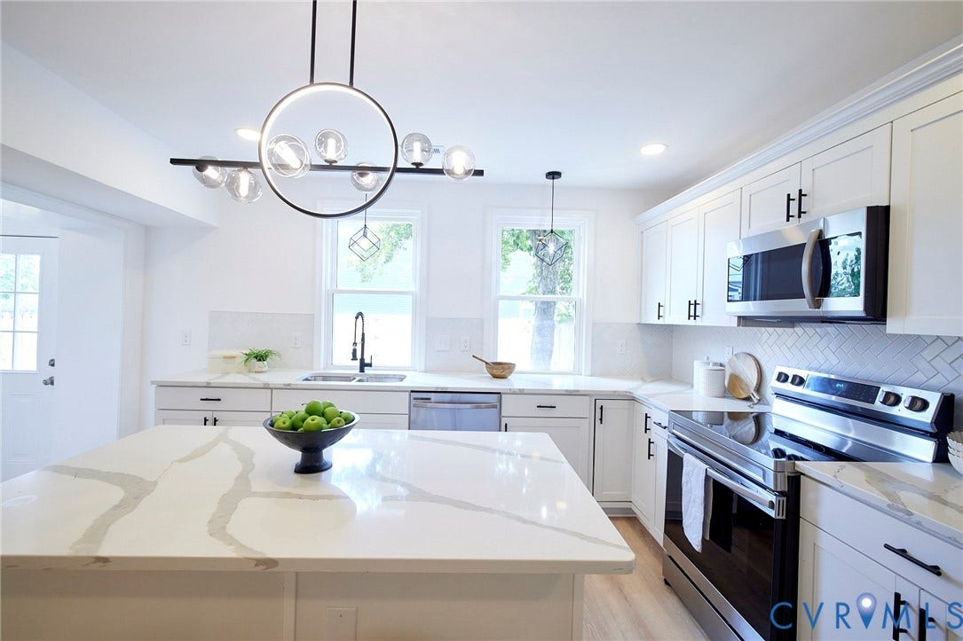 3103 Q St, Church Hill, Richmond, VA 23223 White shaker cabinetry, stainless steel appliances, quartz countertops, herringbone tile backsplash, and light wood-finish flooring