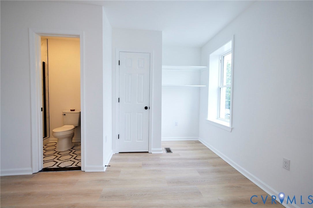 3103 Q St, Church Hill, Richmond, VA 23223 Light wood-finish flooring, built-in shelving, white paneled door, and a full bathroom with patterned floor tiling