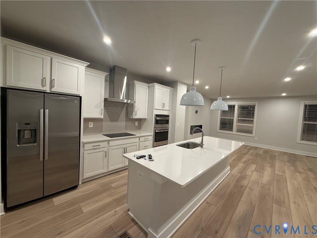 9452 belladdie Way, Glen Allen, VA 23059 Wood-finish flooring throughout, kitchen featuring white shaker cabinetry, stainless steel appliances, a center island with sink, and recessed lighting