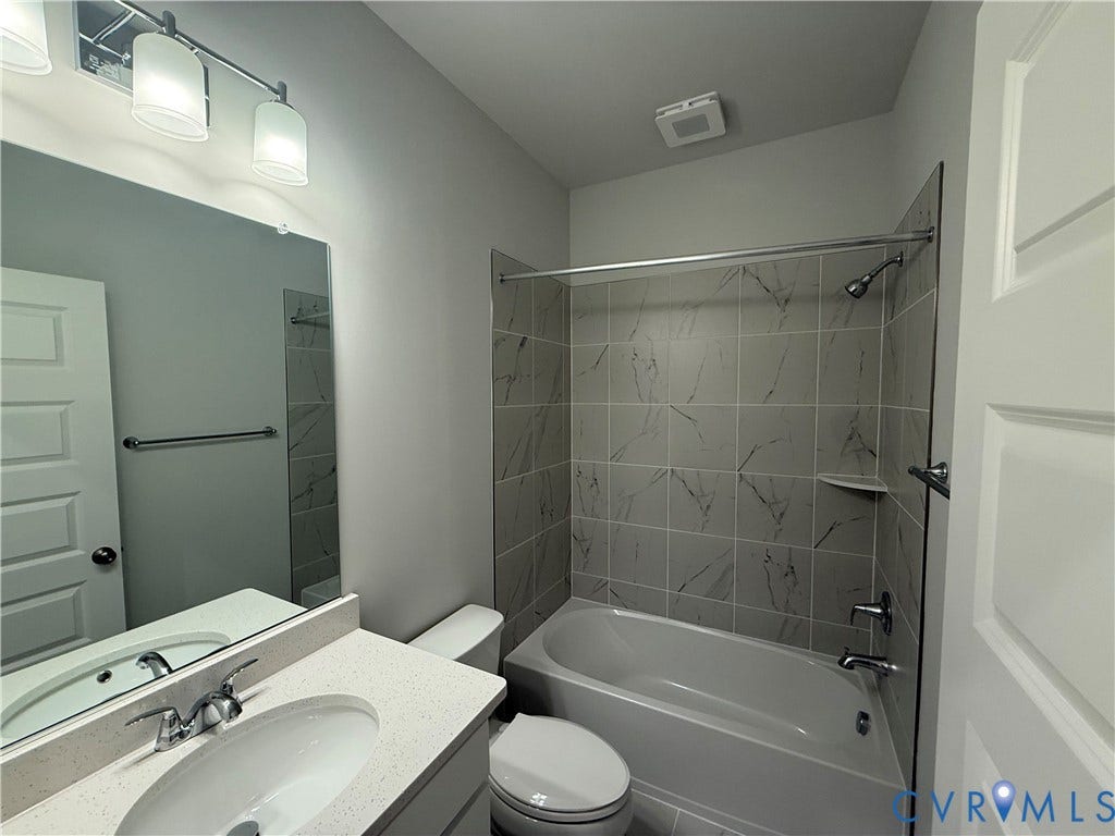9452 belladdie Way, Glen Allen, VA 23059 Bathroom featuring a vanity with an integrated sink, a large wall-mounted mirror, a tub/shower combination with tile surround, and an overhead light fixture