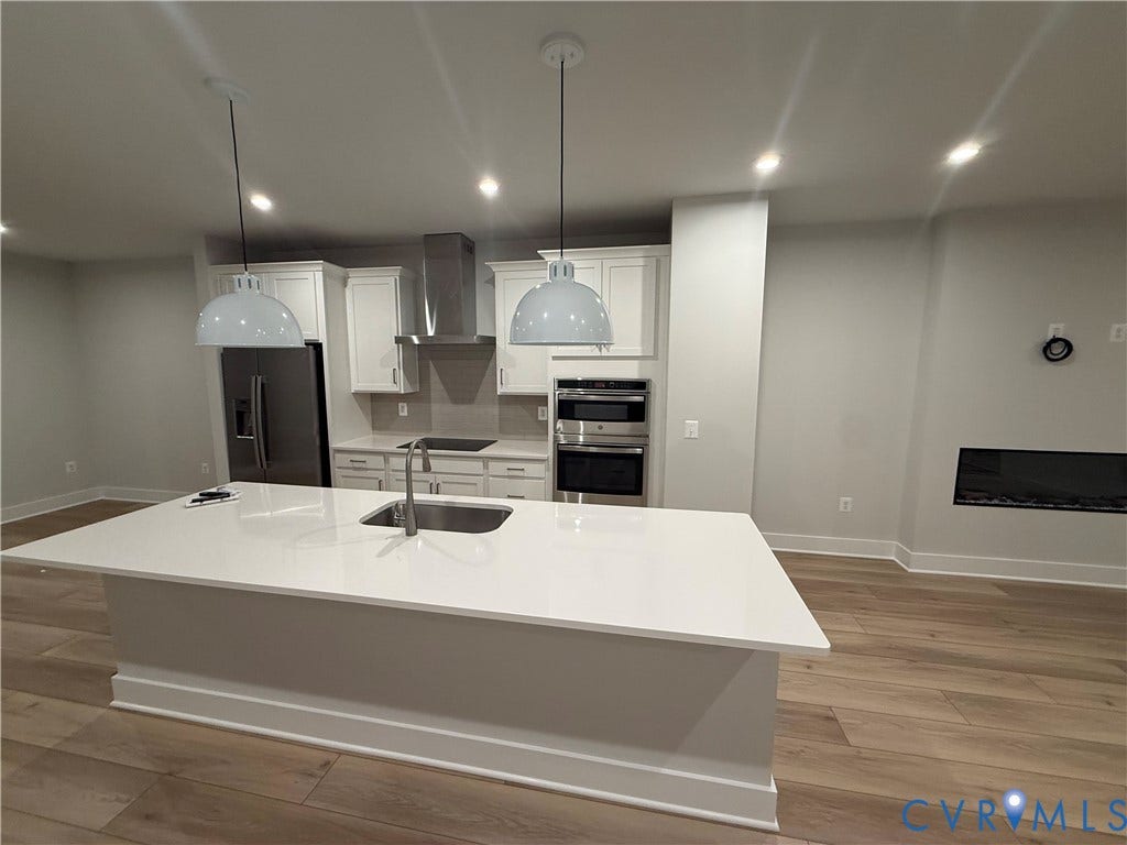 9452 belladdie Way, Glen Allen, VA 23059 Kitchen featuring a large island with an undermount sink, stainless steel appliances, white cabinetry, and wood-finish flooring