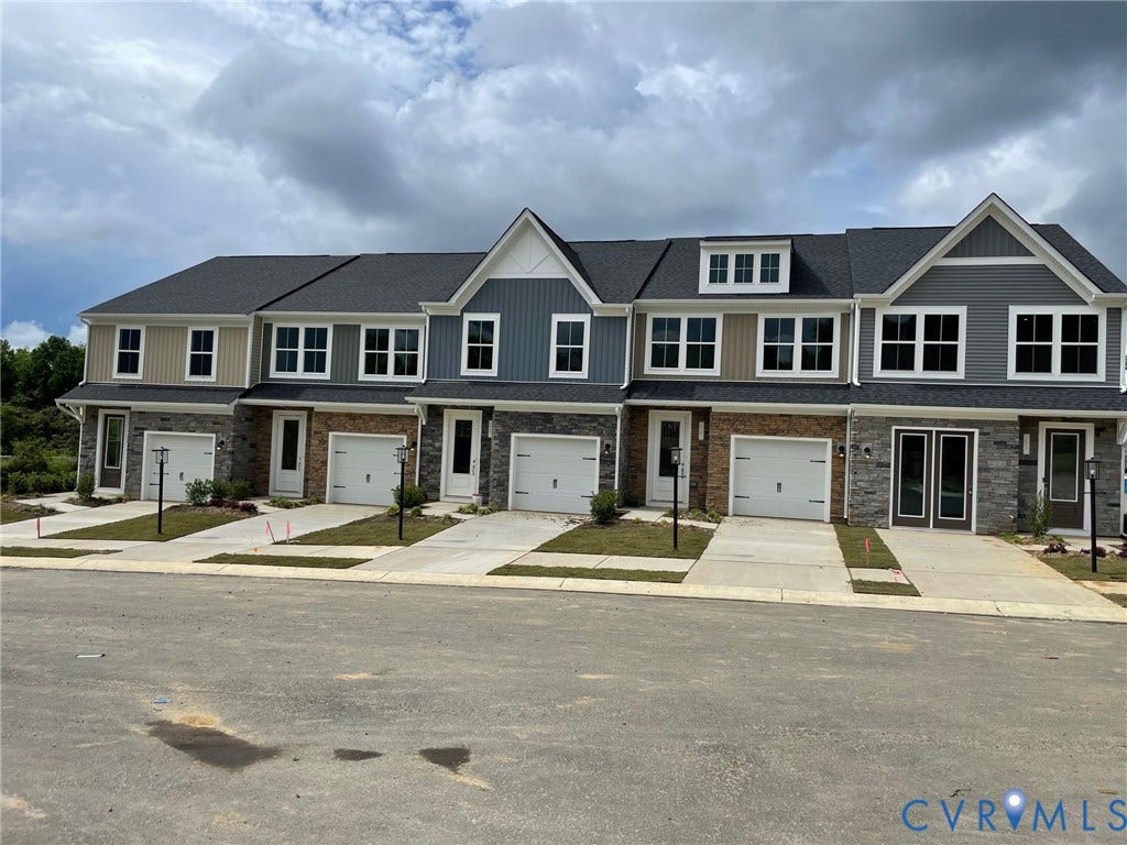 Contemporary townhomes featuring varied siding finishes, stone accents, black shingle roofing, and integrated single-car garages