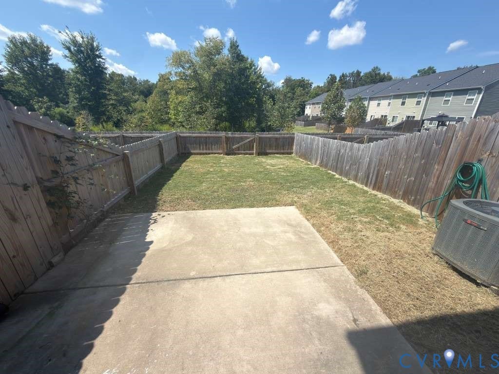 Fenced backyard featuring a concrete patio and a wooden privacy fence with a gate