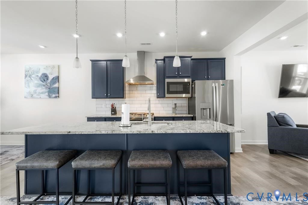 12221 Dutch Elm Circle, Midlothian, VA 23112 Kitchen with a central island featuring a light-toned countertop, dark blue cabinetry, stainless steel appliances, a subway tile backsplash, and recessed lighting