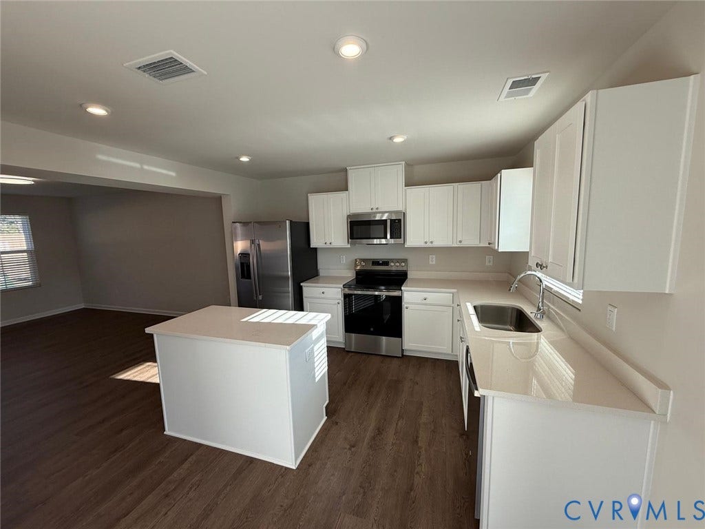 5409 Canterbury Ridge Way, Richmond, VA 23224 White shaker-style cabinetry, stainless steel appliances, wood-finish flooring, recessed lighting, and a kitchen island with a light-toned countertop