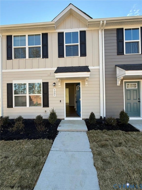 5409 Canterbury Ridge Way, Richmond, VA 23224 Modern townhome exterior featuring light-colored siding, dark shutters, an accent gable, and a concrete pathway