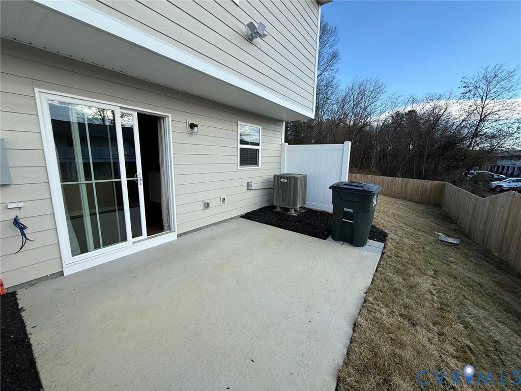 5409 Canterbury Ridge Way, Richmond, VA 23224 Concrete patio with a sliding glass door, flanked by an exterior wall with horizontal siding and a window