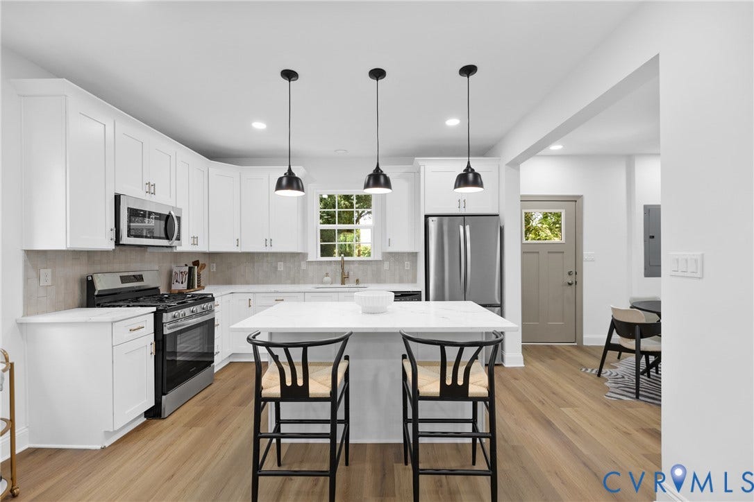 Kitchen featuring stainless steel appliances, white cabinetry, a large center island, pendant lighting, and wood-finish flooring