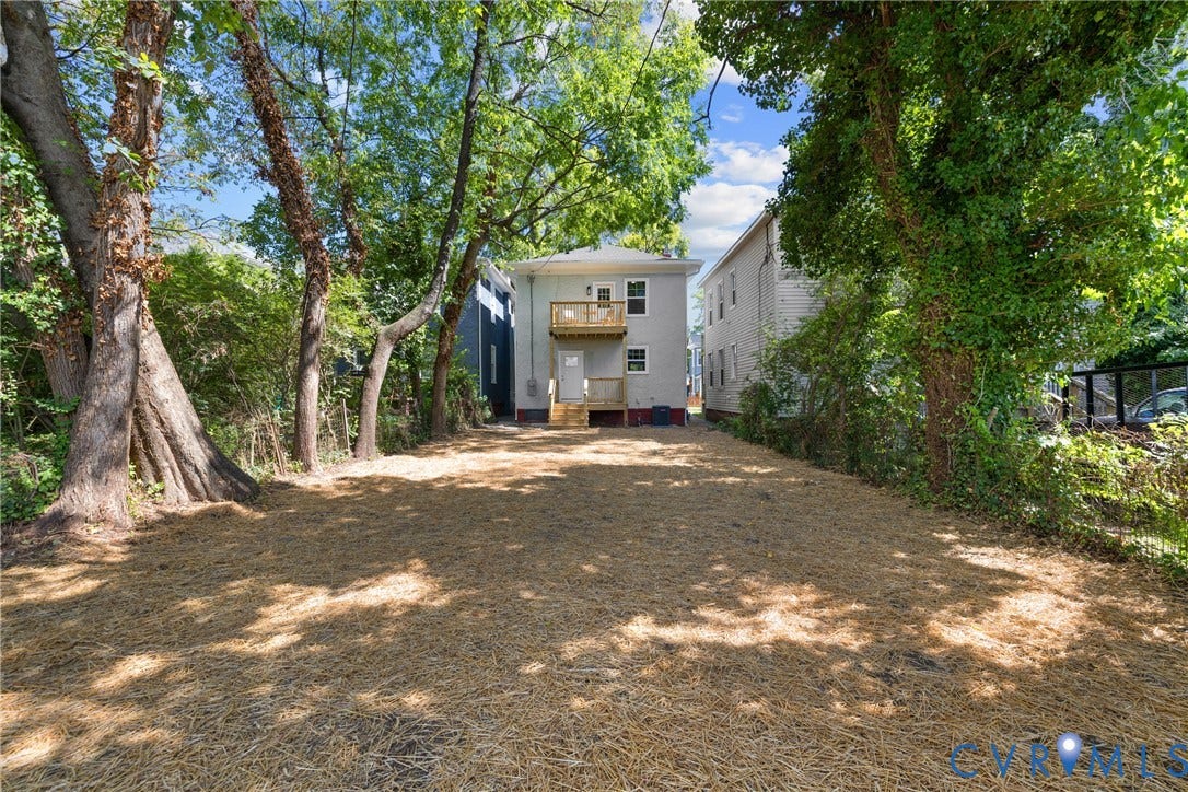 Expansive yard featuring mature trees, a multi-level deck, and a second-story balcony