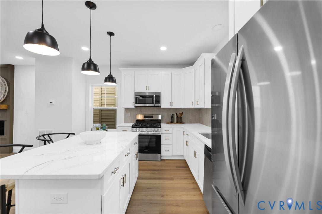 Kitchen featuring white shaker cabinetry, stainless steel appliances, a center island with a stone-finish countertop, and wood-finish flooring