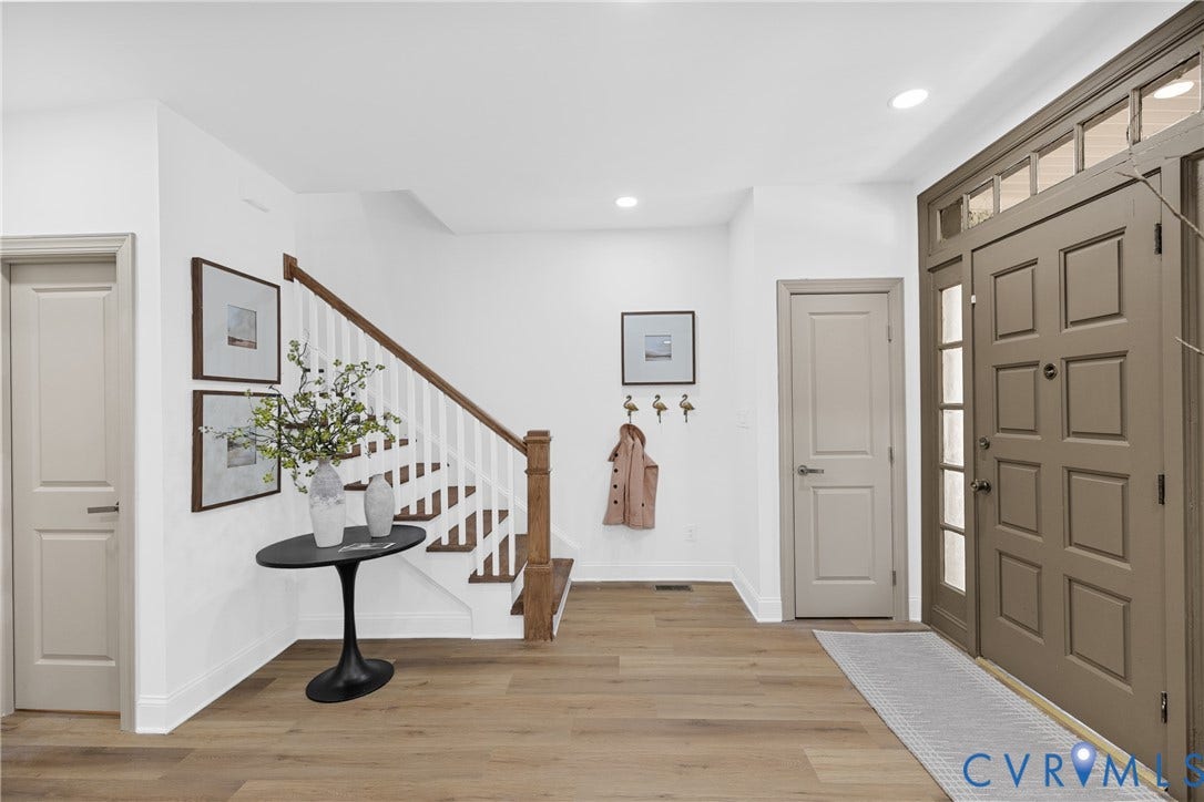 Entry foyer featuring wood-finish flooring, a staircase with white risers and wood treads, a paneled entry door with sidelights, and recessed lighting