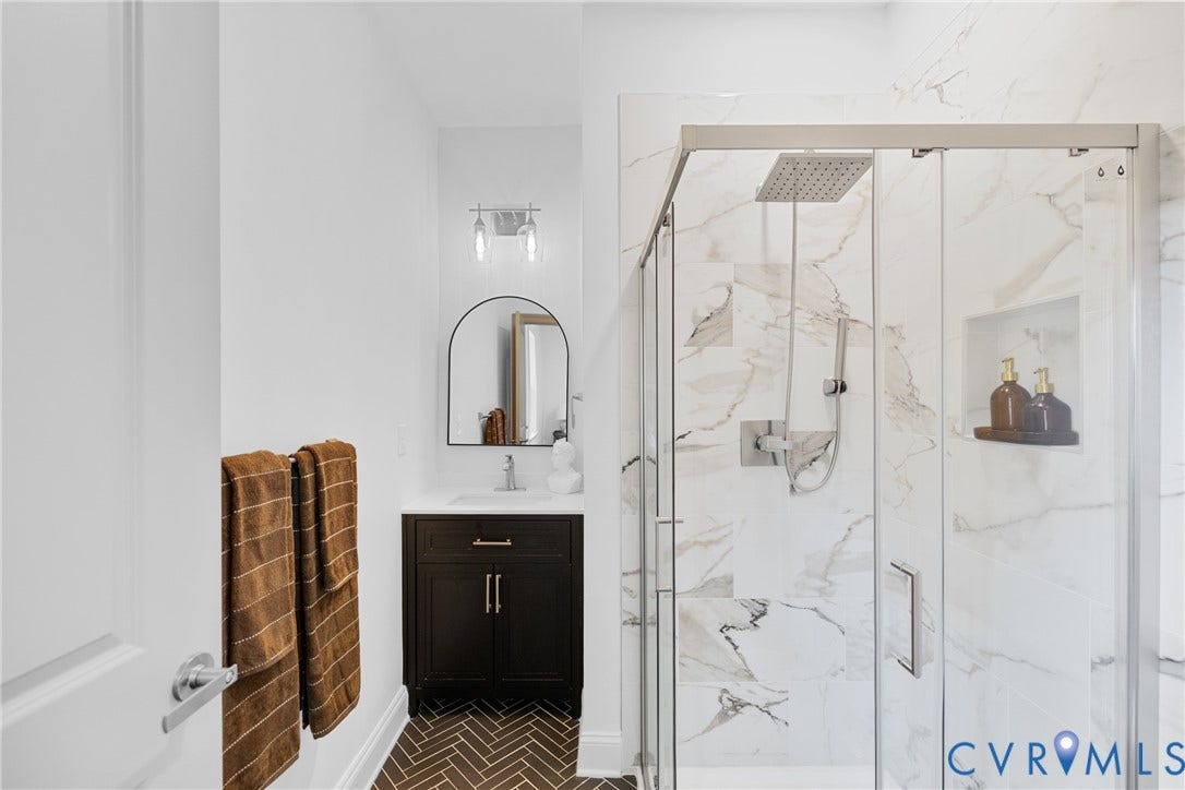 Glass-enclosed shower with a rainfall showerhead, tiled walls, and a built-in niche