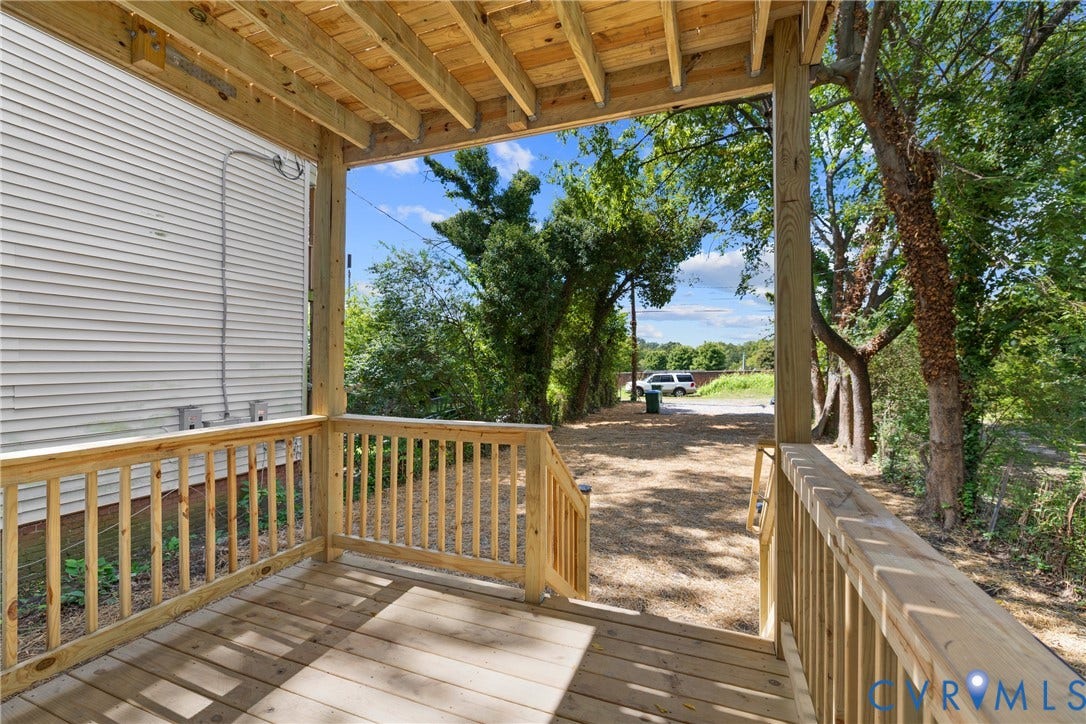 Covered outdoor deck with wooden railing and exposed wood joist ceiling