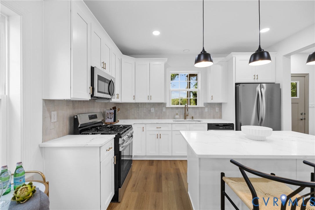 White cabinetry, stainless steel appliances, wood-finish flooring, white countertop surfaces, and a tiled backsplash