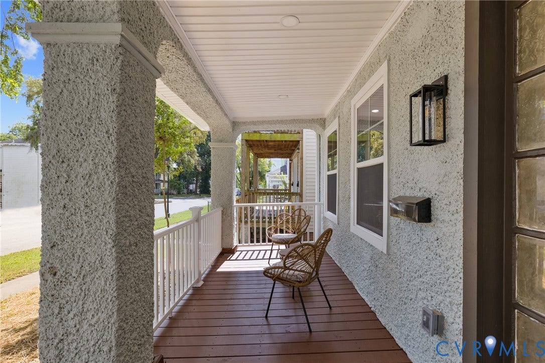 Covered front porch featuring wood-finish flooring, white railing, and stucco columns