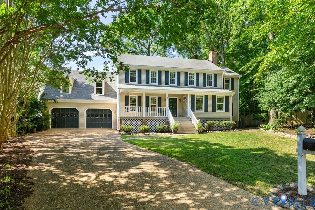 2416 Mountainbrook Drive, Crown Grant, Henrico, VA 23233 Two-story residence featuring light-colored siding with dark shutters, an expansive gravel driveway, a two-car garage, a covered front porch, and a manicured front lawn