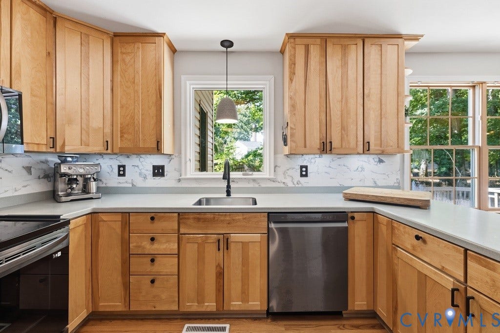 2416 Mountainbrook Drive, Crown Grant, Henrico, VA 23233 Wood-finish cabinetry with matte black hardware, light-toned countertops, modern pendant lighting, stainless steel dishwasher, and a large window with exterior views