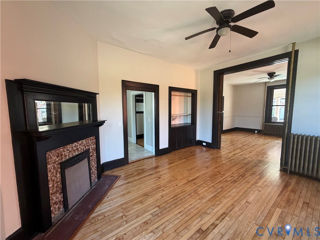 715 High Street, Petersburg, VA 23803 Hardwood flooring throughout, a decorative fireplace with a tile surround, dark wood trim, and a ceiling fan