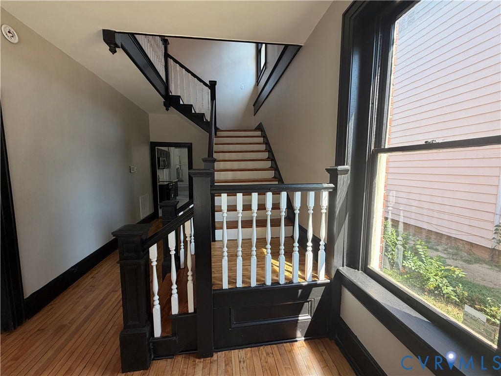 715 High Street, Petersburg, VA 23803 Hardwood flooring throughout, featuring a staircase with painted wood newel posts and balusters, and a large window with dark trim