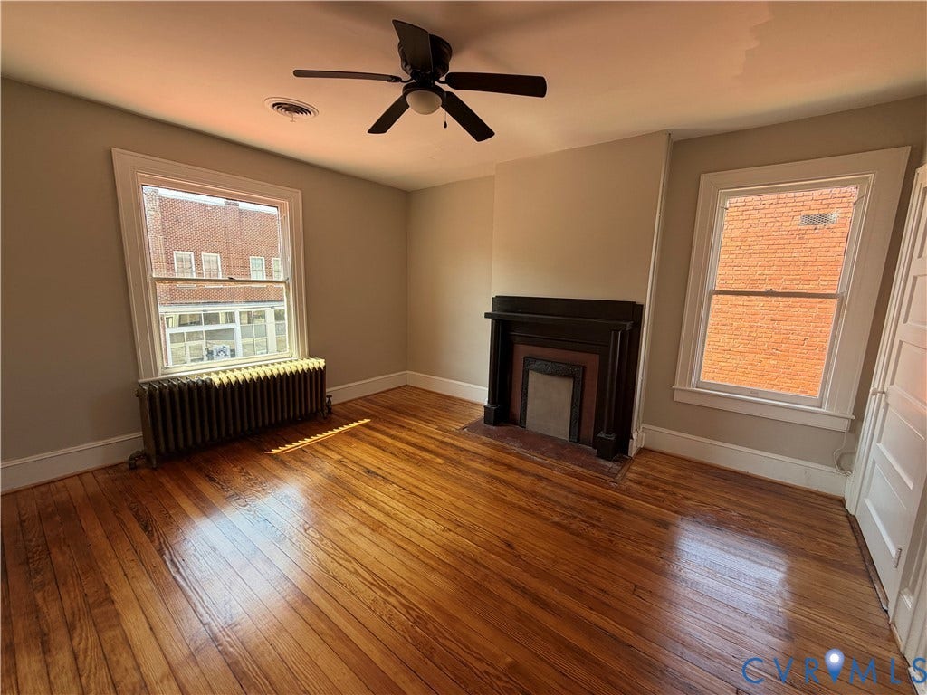 715 High Street, Petersburg, VA 23803 Hardwood flooring, decorative fireplace, ceiling fan, and two windows providing natural illumination