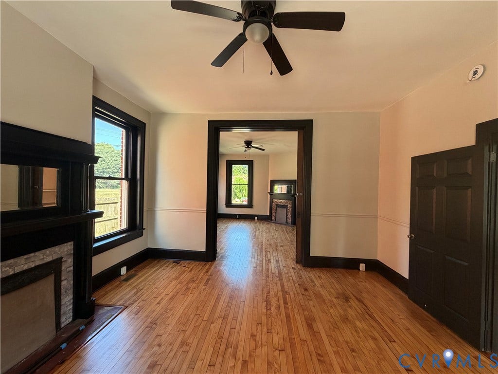 715 High Street, Petersburg, VA 23803 Hardwood flooring throughout, a ceiling fan with light fixture, and a decorative fireplace with a stone surround
