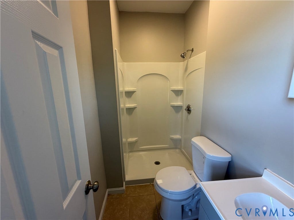 715 High Street, Petersburg, VA 23803 Walk-in shower with integrated shelving, white vanity with integrated sink, toilet, and neutral wall tones