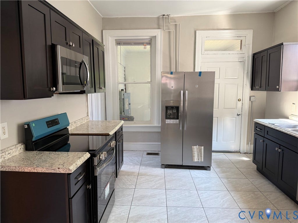 715 High Street, Petersburg, VA 23803 Equipped kitchen featuring dark wood-finish cabinetry, light-toned countertops, tile flooring, stainless steel microwave, and a stainless steel side-by-side refrigerator