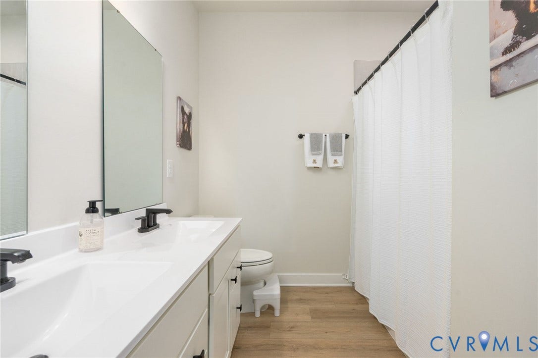 8045 Lake Laurel Lane, #B, Laurel Oak Condos, Glen Allen, VA 23060 Dual white rectangular sinks, black matte faucets, wood-finish flooring, and a shower with a white curtain