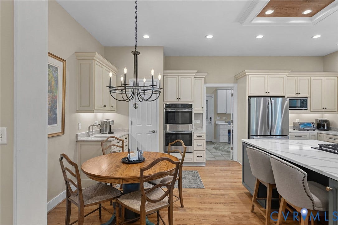447 Tranquility Road, Reedville, VA 22539 Kitchen featuring wood-finish flooring, white cabinetry, stainless steel appliances, and a central island with a light-toned countertop